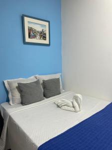 a bed in a room with a blue wall at Hostel Recanto Verde - Conforto e Tranquilidade em Campo Grande in Campo Grande