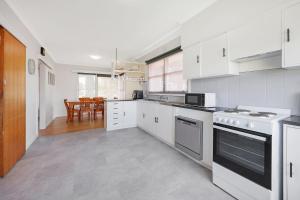 a kitchen with white appliances and a dining room at Jack & Bias Cottage in Warrnambool
