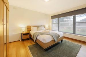 a bedroom with a bed and a large window at Jack & Bias Cottage in Warrnambool