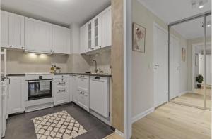 an empty kitchen with white cabinets and appliances at Elegant apartment in Oslo