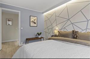 a bedroom with a large white bed with a geometric headboard at Elegant apartment in Oslo