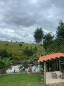 a gazebo with two benches and a river at Pousada San Matheus in São Miguel Arcanjo