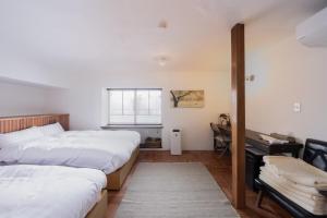 a bedroom with two beds and a desk in it at 佐藤理容Inn in Hakodate