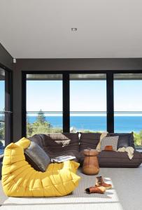 a living room with a yellow couch and some windows at Thirteen Bowman - Sunshine Beach, Ocean Views in Sunshine Beach