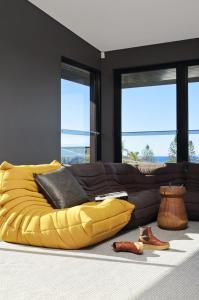 a yellow bed in a living room with a couch at Thirteen Bowman - Sunshine Beach, Ocean Views in Sunshine Beach