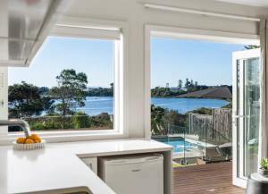 a kitchen with large windows and a view of the ocean at Riverside Retreat with River views in Auckland