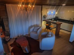 a living room with two chairs and a table at Chalé Recanto do Pimenta 02 in Venda Nova do Imigrante