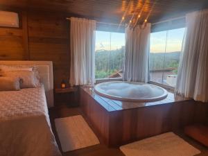 a large bath tub in a room with a window at Chalé Recanto do Pimenta 02 in Venda Nova do Imigrante