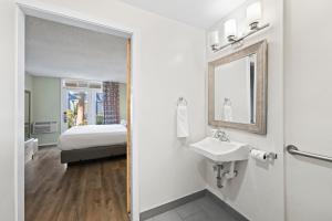 a bathroom with a sink and a bed at Marina Village Inn in Alameda