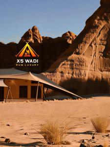 a building in the desert next to a rock formation at X5 wadi Rum Luxury in Wadi Rum +11 photos