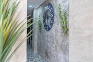 a clock on the side of a wall with plants at Casa Presentacion Adaz Hotel in Santa Marta