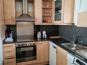a kitchen with wooden cabinets and a stove top oven at Seafront apartment S'Abanell Central Park with pool in Blanes +32 photos