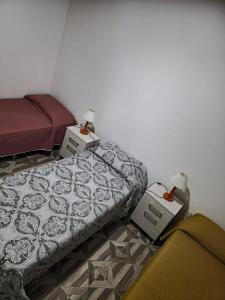 a bedroom with two beds and a table with a lamp at Departamentos Los Árboles in San Francisco del Monte de Oro