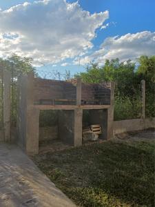 a wooden bench sitting in the grass near a fence at Departamentos Los Árboles in San Francisco del Monte de Oro