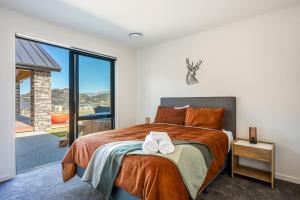 a bedroom with a large bed with two towels on it at Carrickmore Lodge in Wanaka