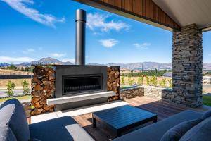 a fireplace on a patio with a view of mountains at Carrickmore Lodge in Wanaka