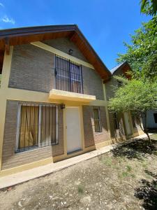 a brick house with a white door and a tree at cabanas nahuel in Villa General Belgrano