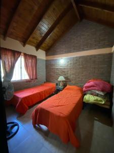 two beds in a room with red sheets at cabanas nahuel in Villa General Belgrano