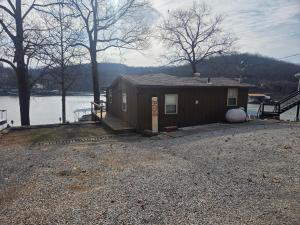 a small house on the shore of a body of water at Shady Valley Lakefront Cottage in Sunrise Beach