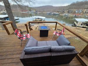 a couch on a deck with a table and chairs at Shady Valley Lakefront Cottage in Sunrise Beach