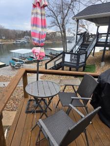 a table and chairs and an umbrella on a deck at Shady Valley Lakefront Cottage in Sunrise Beach