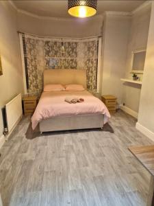 a bedroom with a bed with pink sheets and wooden floors at Red Lions Liverpool in Liverpool
