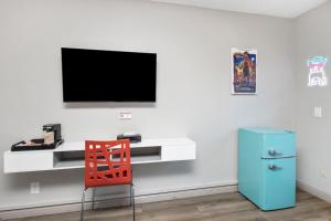 a red chair and a desk with a television on a wall at Royal Pagoda Motel Dodger Stadium in Los Angeles