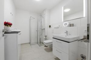 a white bathroom with a toilet and a sink at Bernsteinquartier, Whg 01 03 in Kölpinsee +6 photos