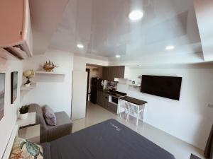 a small kitchen and living room with a couch and a television at Mai Khao 777 Beach Condo in Ban Mai Salae