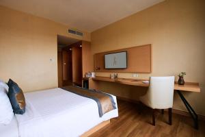 a hotel room with a bed and a desk and a tv at Horison Diana Timika in Timika