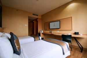a hotel room with two beds and a desk at Horison Diana Timika in Timika