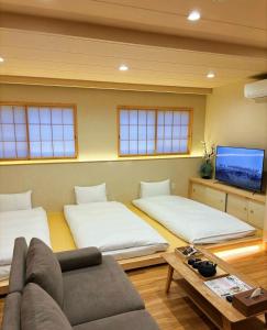 a room with two beds and a couch and a tv at Ueno K in Tokyo