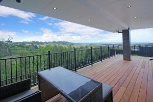 a balcony with a table on a wooden deck at Your Private Escape with city views in Auckland