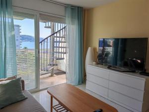 a living room with a television and a balcony at Seafront apartment S'Abanell Central Park with pool in Blanes