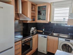 a kitchen with wooden cabinets and a washer and dryer at Seafront apartment S'Abanell Central Park with pool in Blanes