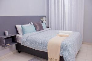 a bedroom with a bed with a blanket on it at The Views Apartments in Kariba