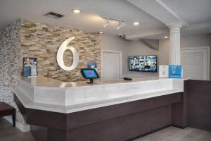 a lobby with a counter with a tv on a wall at Motel 6 Lake City, FL – Medical Center in Lake City