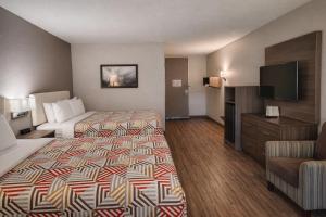 a hotel room with two beds and a flat screen tv at Motel 6 Lake City, FL – Medical Center in Lake City