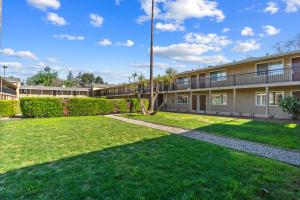 an apartment building with a lawn in front of it at Rose Garden Inn - San Jose Airport in San Jose