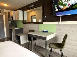 a kitchen with a table and two chairs and a tv at Le George Motel in Port Macquarie