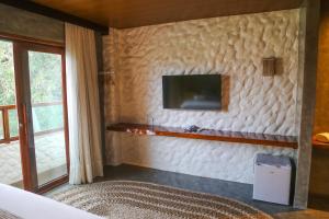 a bedroom with a white wall with a tv on it at Hotel Kanto Do Chico Conceito in Icaraí
