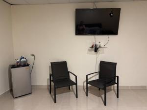 two black chairs and a television on a wall at Fourth Studio and Festivities in Guararé