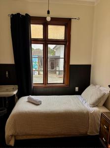 a bedroom with a bed in front of a window at Waitaki Hotel Kurow in Kurow