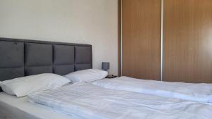 a bedroom with two beds with white sheets and a headboard at Apartman Andjela in Tivat