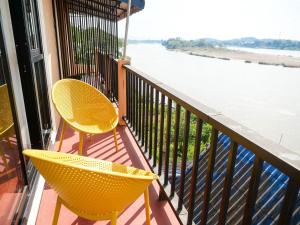 two yellow chairs sitting on a balcony overlooking the water at Riverside Houayxay Hotel in Ban Houayxay