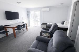 a living room with a couch and a desk and a bed at BKs Premier Motel Esplanade in Lower Hutt
