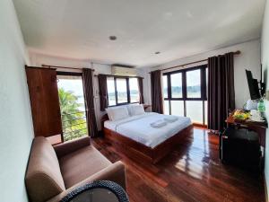 a bedroom with a bed and a couch and windows at Riverside Houayxay Hotel in Ban Houayxay