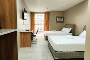 a hotel room with two beds and a desk at LTG Grand Hotel Cebu in Cebu City