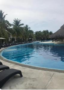 a large swimming pool with chairs and palm trees at Villa en Terrasol Diamante in Acapulco