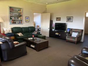 a living room with a green couch and a tv at Mirradong Cottage in Berambing